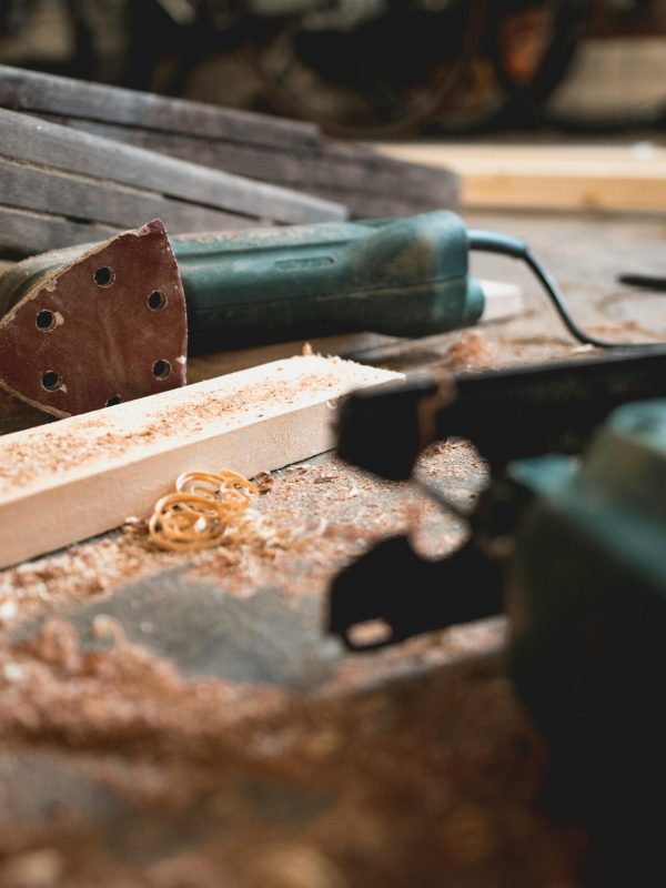 Close-up of various woodworking tools in a workshop, featuring wood shavings and equipment.